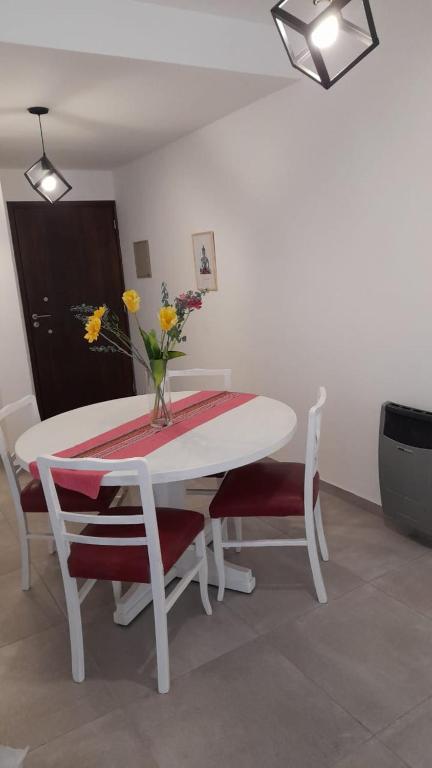 una mesa blanca y sillas con un jarrón de flores. en Bello Departamento en Gran Mendoza en Godoy Cruz
