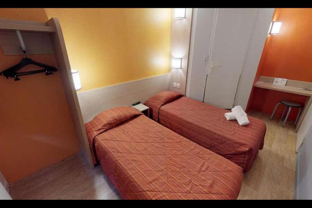 a hotel room with two beds in a room at Premiere Classe Cambrai Proville in Cambrai