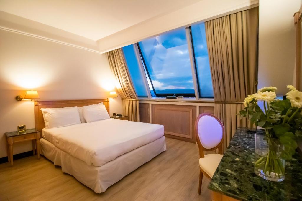 une chambre d'hôtel avec un lit et un vase de fleurs dans l'établissement SHG Hotel De La Ville, à Vicence