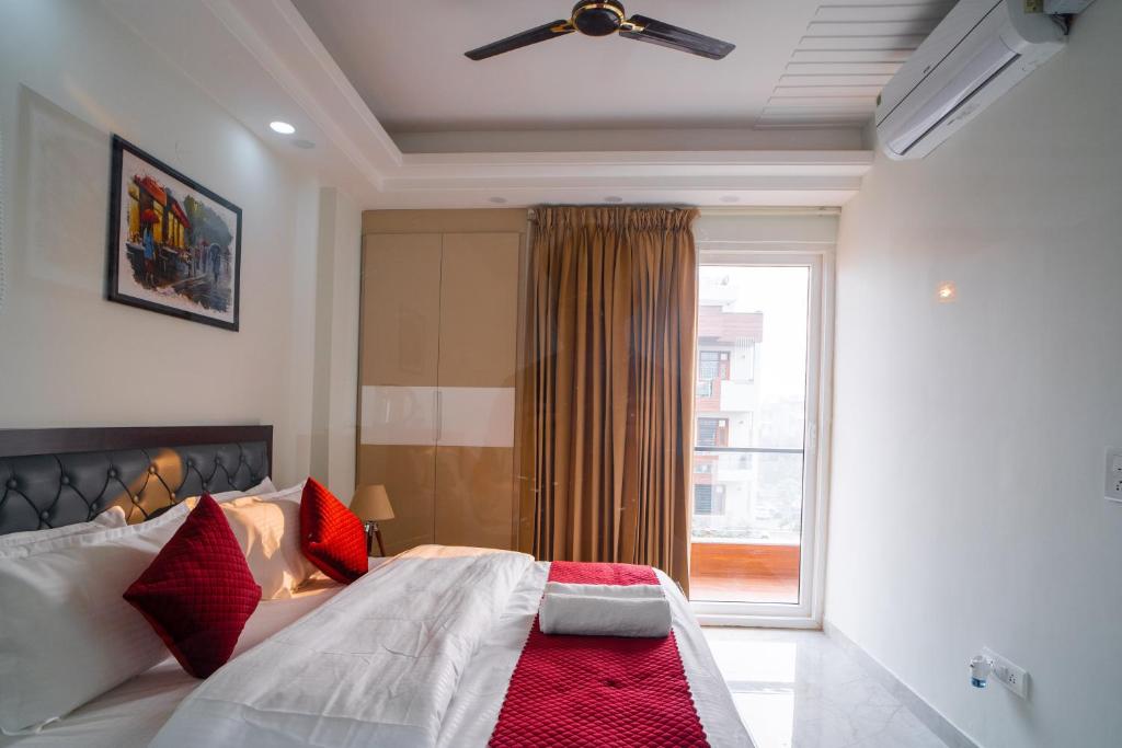 a bedroom with a bed with red pillows and a window at The Lodgers 1 BHK Serviced Apartment Golf Course Road Gurgaon in Gurgaon