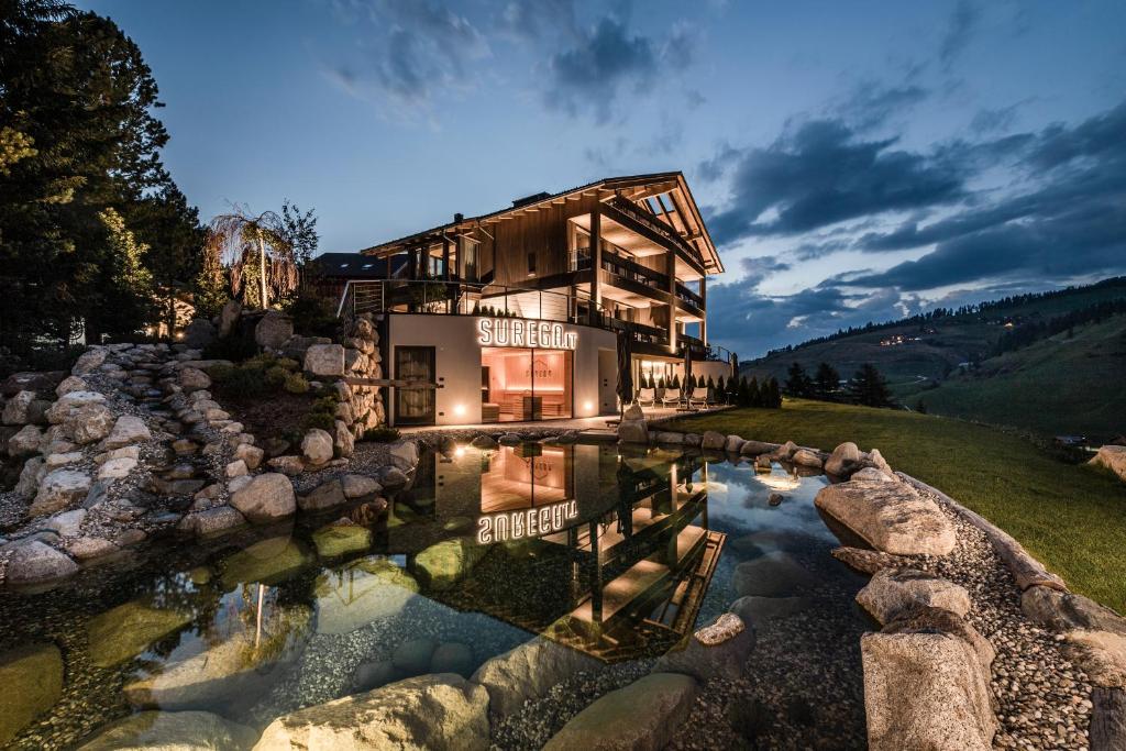 une maison avec un étang en face de celle-ci dans l'établissement Surega - Idyllic Farmhouse, à San Cassiano