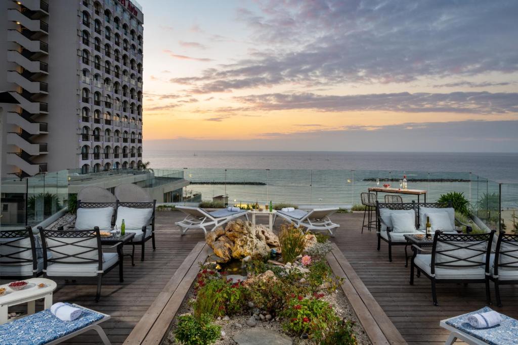 een patio met tafels en stoelen en de oceaan bij Maxim Design Hotel 3 Star Superior in Tel Aviv