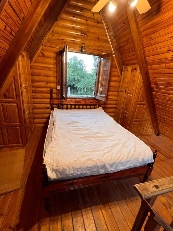 a bed in a wooden room with a window at Cabaña in La Rioja