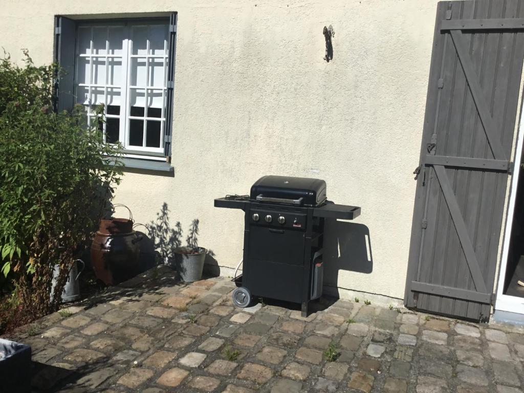 a grill sitting outside of a house with two doors at le gîte de Martine en Baie de Somme in Lanchères
