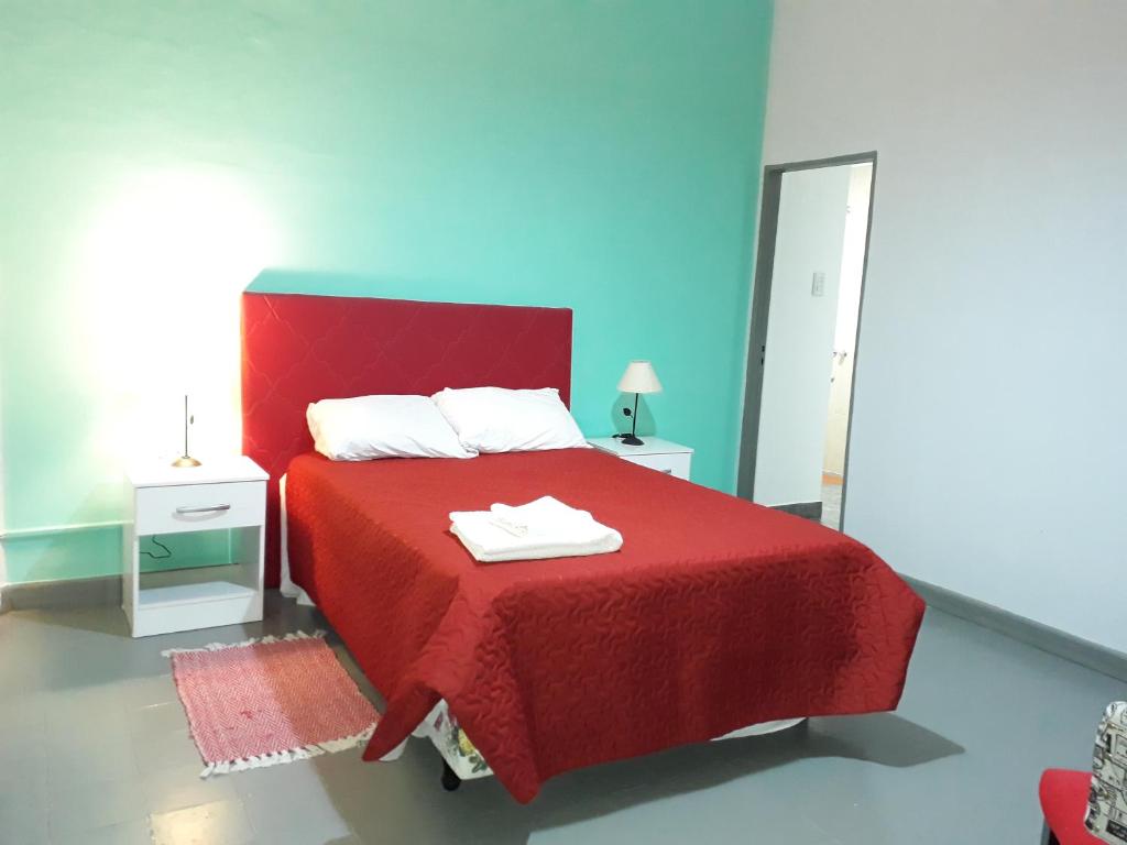 cama roja con manta roja y espejo en Departamentos Santa Fe en Salta