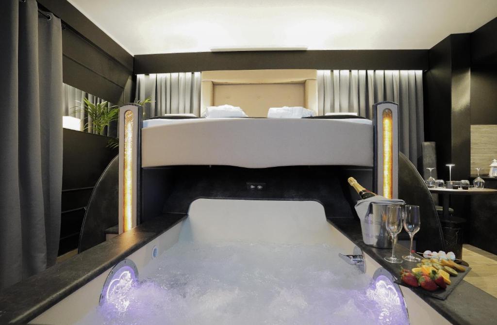 a bedroom with a tub with a bed in the background at Tomà Suites - Il Nido d’Amore in Rome