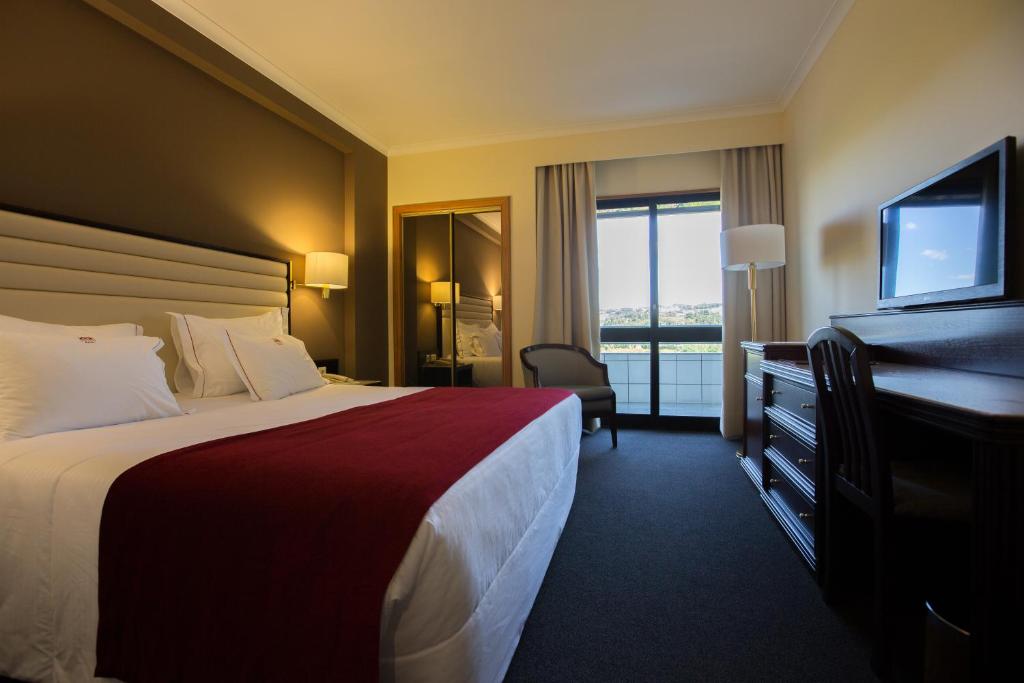 a hotel room with a bed and a desk and a television at Hotel Miracorgo in Vila Real