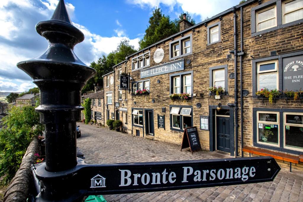 um sinal de rua em frente a um edifício de tijolos em The Fleece Inn em Haworth