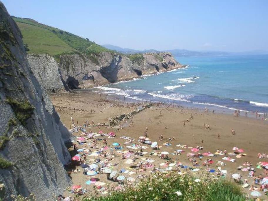 a beach with a bunch of people with umbrellas at APARTAMENTO DANAE centro in Zumaia
