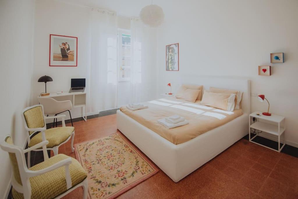 a white bedroom with a bed and a desk and a chair at A casa di Giulia in Latina