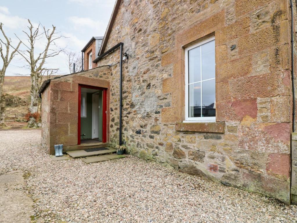 um edifício de tijolos com uma porta vermelha e uma janela em White Hillocks Farm House em Inchmill
