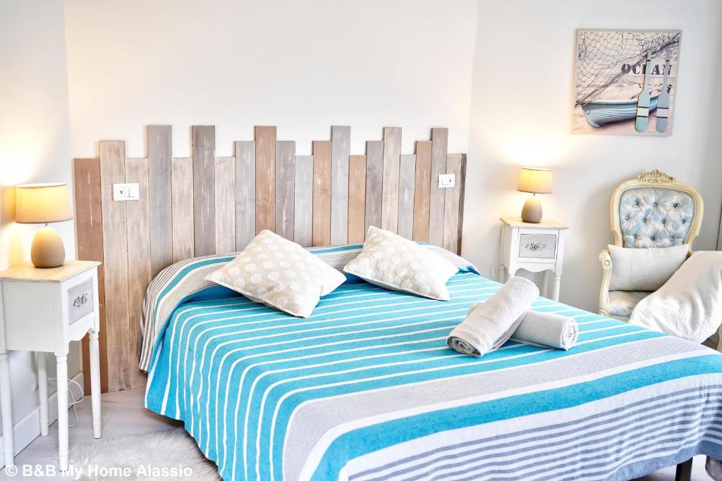 um quarto com uma cama com um cobertor listrado azul e branco em Bed & Breakfast My Home - Alassio em Alassio