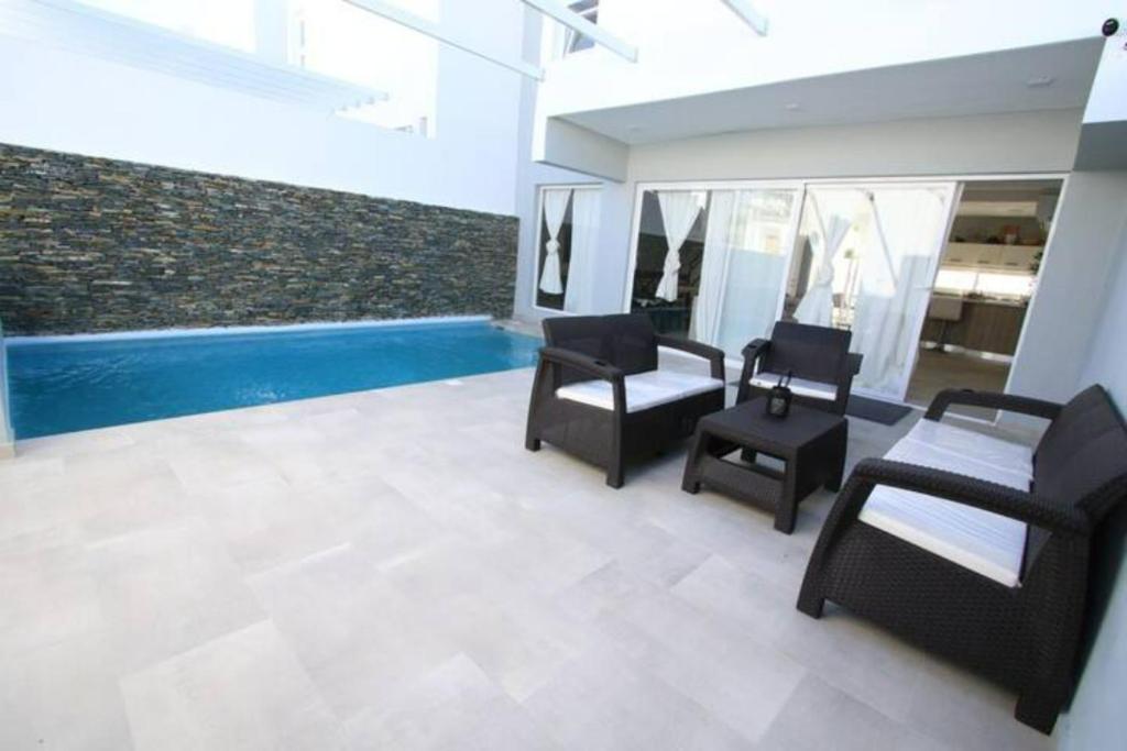 a living room with black chairs and a swimming pool at Villa bayahibe 103 in San Rafael del Yuma