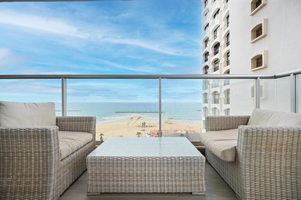 a balcony with wicker chairs and a table and the beach at Orchid Hotel by HolyGuest in Tel Aviv