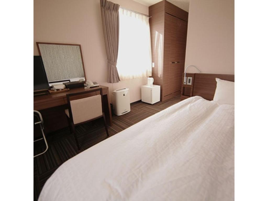 a bedroom with a bed and a desk and a mirror at Business Hotel Goi Onsen - Vacation STAY 78233v in Ichihara