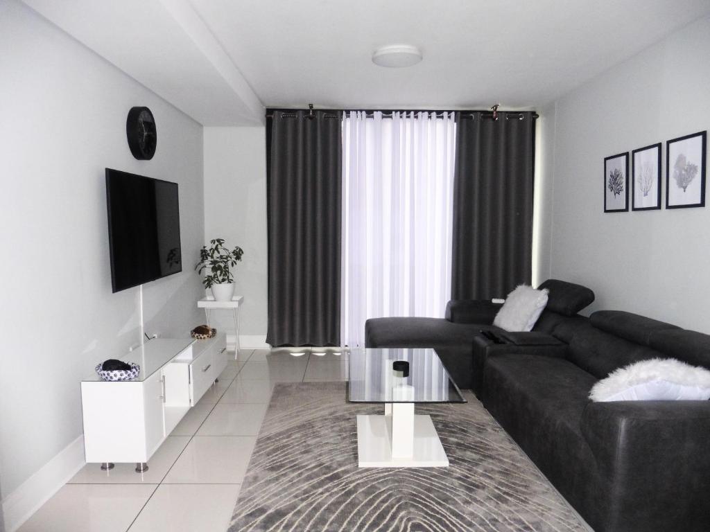 a living room with a black couch and a tv at Home away from Home in Windhoek