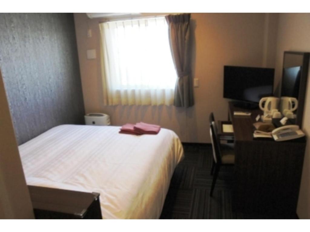 una camera d'albergo con letto, scrivania e finestra di Business Hotel Goi Onsen - Vacation STAY 78235v a Ichihara