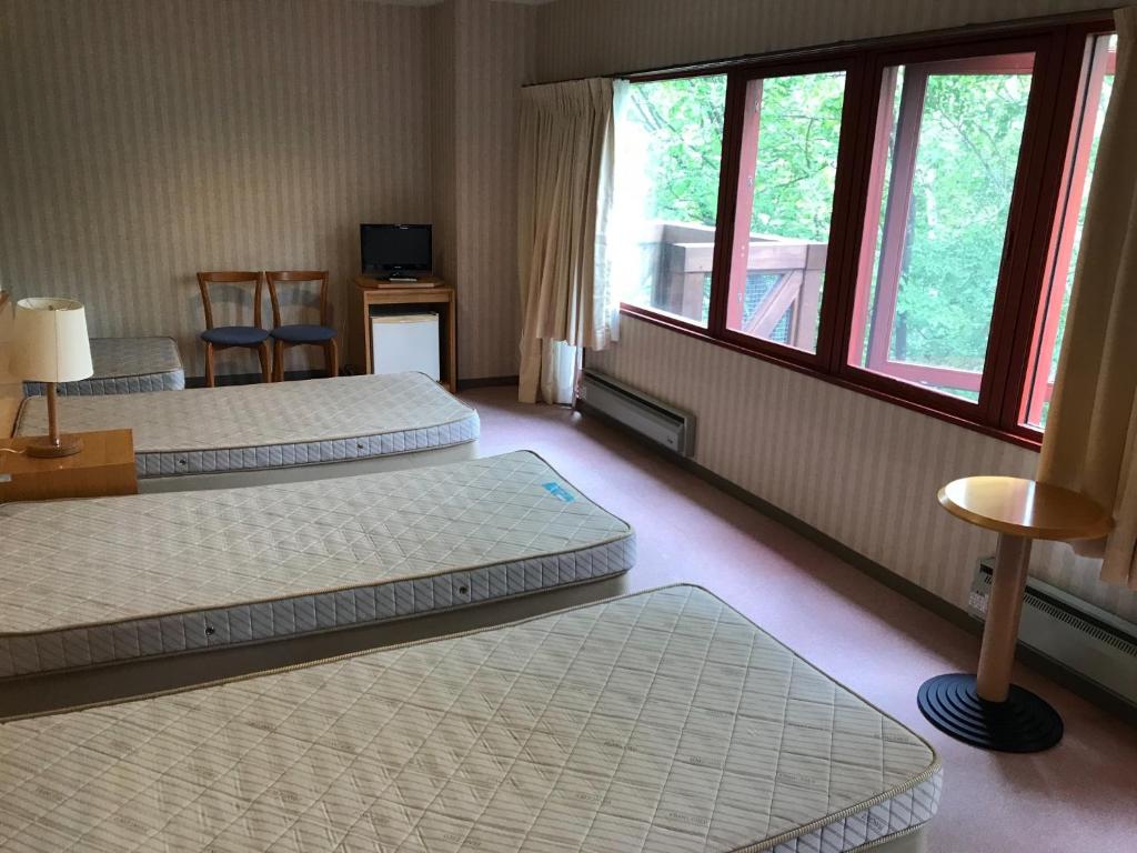 a hotel room with three beds and a window at Aizu Kogen International Human Resources Center - Vacation STAY 65652v in Minamiaizu