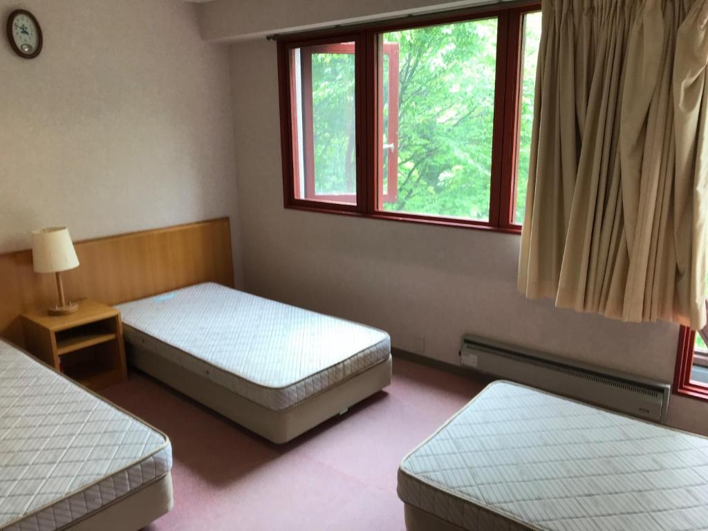 a bedroom with two beds and two windows at Aizu Kogen International Human Resources Center - Vacation STAY 34901v in Minamiaizu