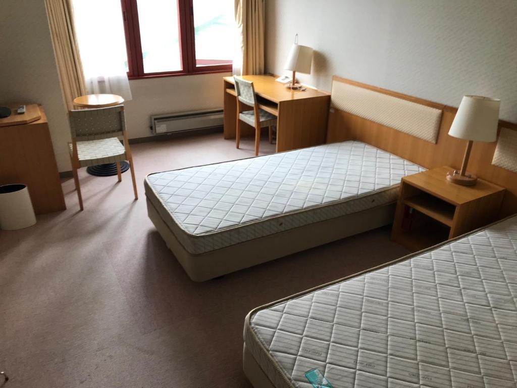 a bedroom with two beds and a desk and a table at Aizu Kogen International Human Resources Center - Vacation STAY 34895v in Minamiaizu