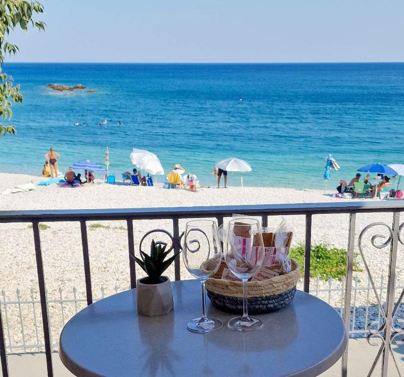 a table with wine glasses on a balcony overlooking the beach at Almia in Khalíkia