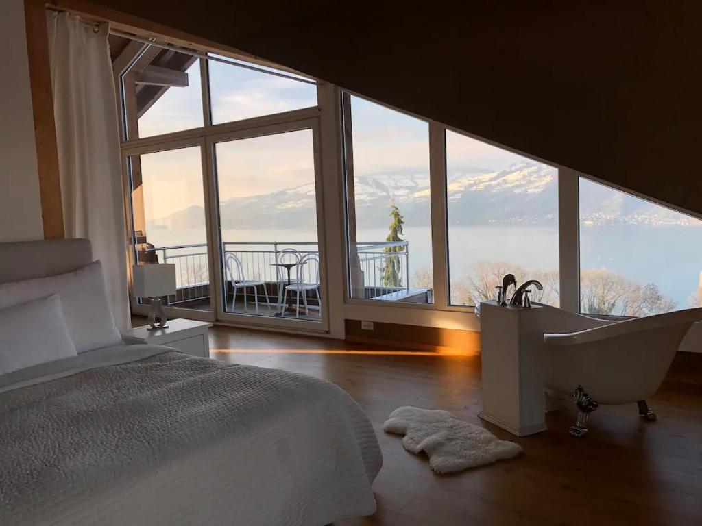 a bedroom with a tub and a view of the ocean at Lakeview Gem in Krattigen