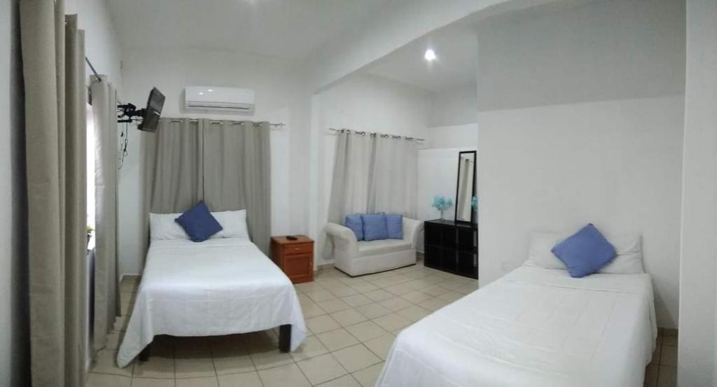 a white room with two beds and a chair at LOS ARCOS in Agua Buena