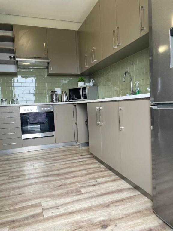 a kitchen with stainless steel appliances and wooden floors at DMN City at Merensky Apartment in Windhoek
