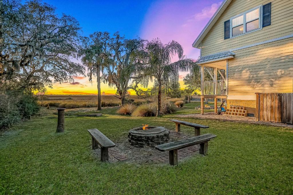 a backyard with two benches and a fire pit at Inviting waterfront cottage with balcony, firepit, marsh views, & washer/dryer in Fernandina Beach