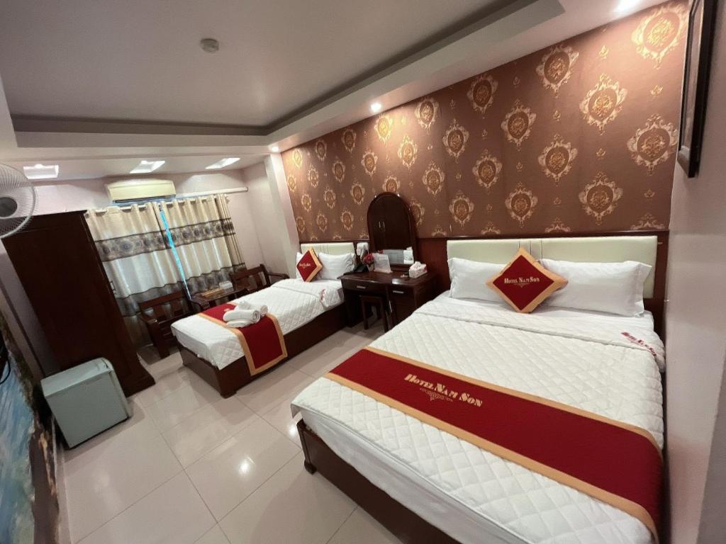 a hotel room with two beds and a desk at Khách Sạn Nam Sơn in Ðoan Xá