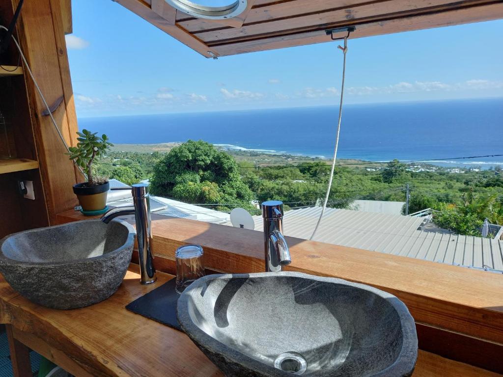 La salle de bains est pourvue de 2 lavabos et offre une vue sur l'océan. dans l'établissement Le Noé, à Saint-Leu