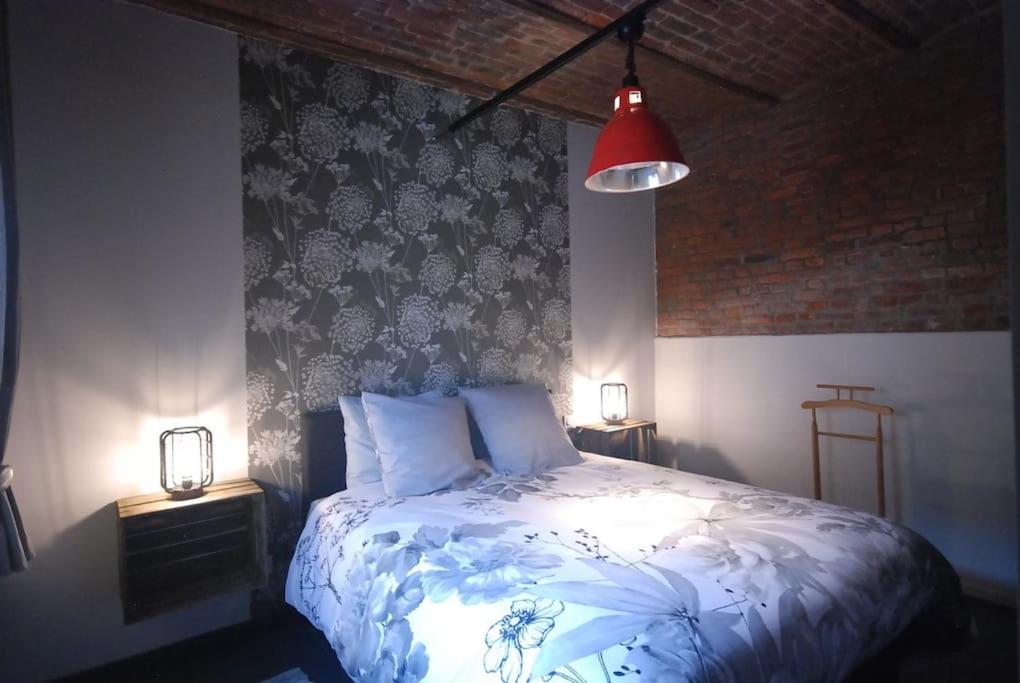 Suite Factory : gîte de charme en Avesnois في Wargnies-le-Petit: غرفة نوم بسرير ومصباح احمر