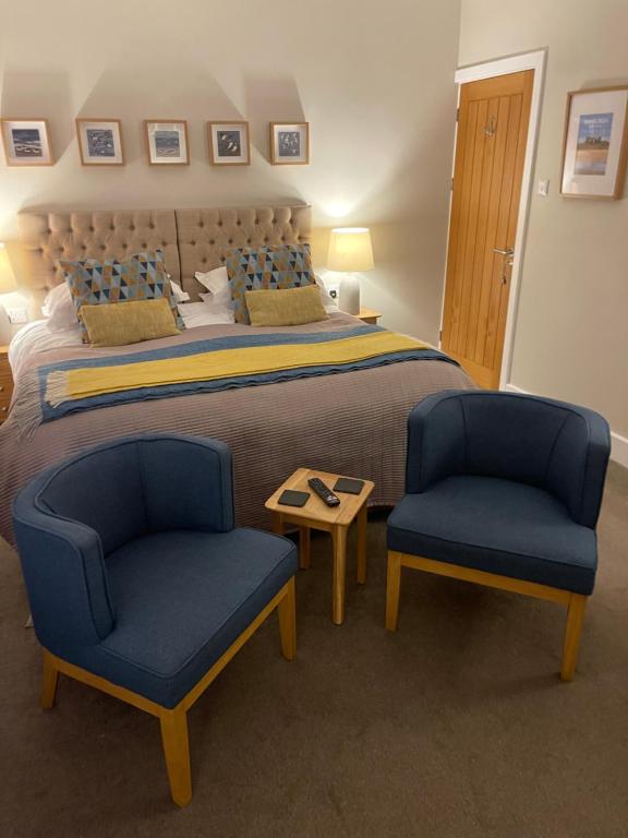 a bedroom with a large bed and two blue chairs at Horncliffe room only accommodation in Seahouses