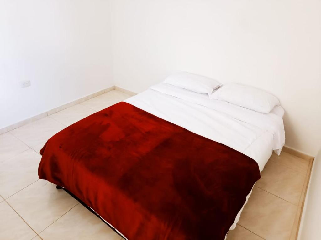 a bed with a red and white blanket on the floor at Apartamentos Pitalito in Pitalito