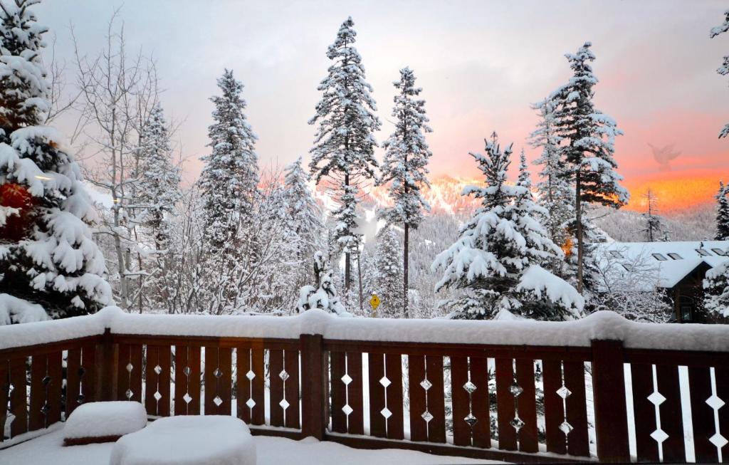 a winter view from a deck with snow covered trees at Highland Huckleberry Lodge in Whitefish
