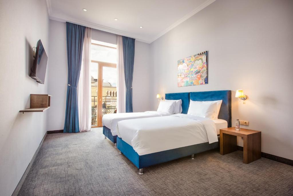 a hotel room with two beds and a window at Alma Boutique Hotel in Tbilisi City