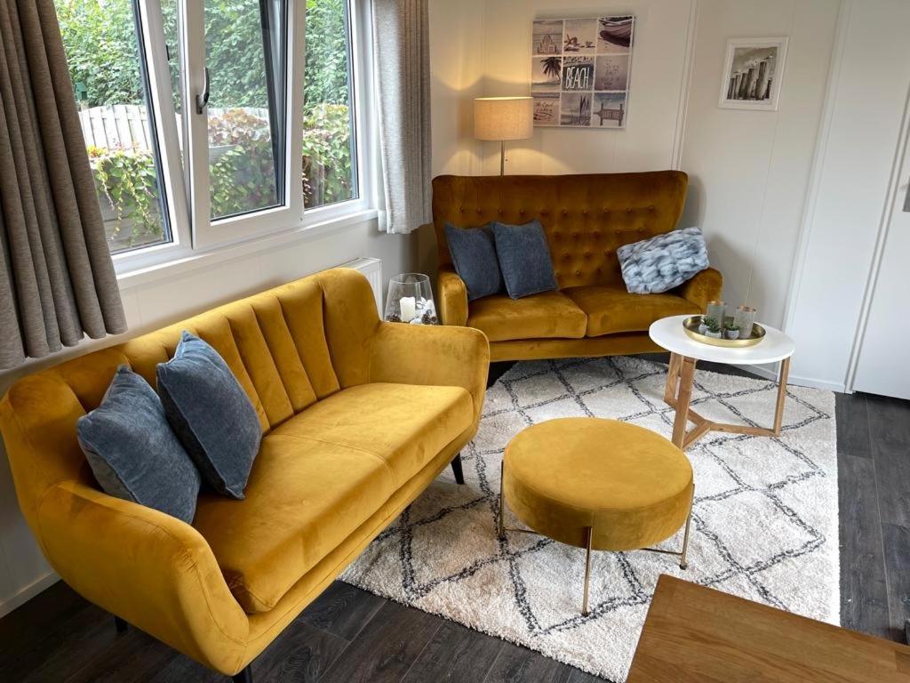 a living room with a yellow couch and a table at Beachhouses Texel in De Koog