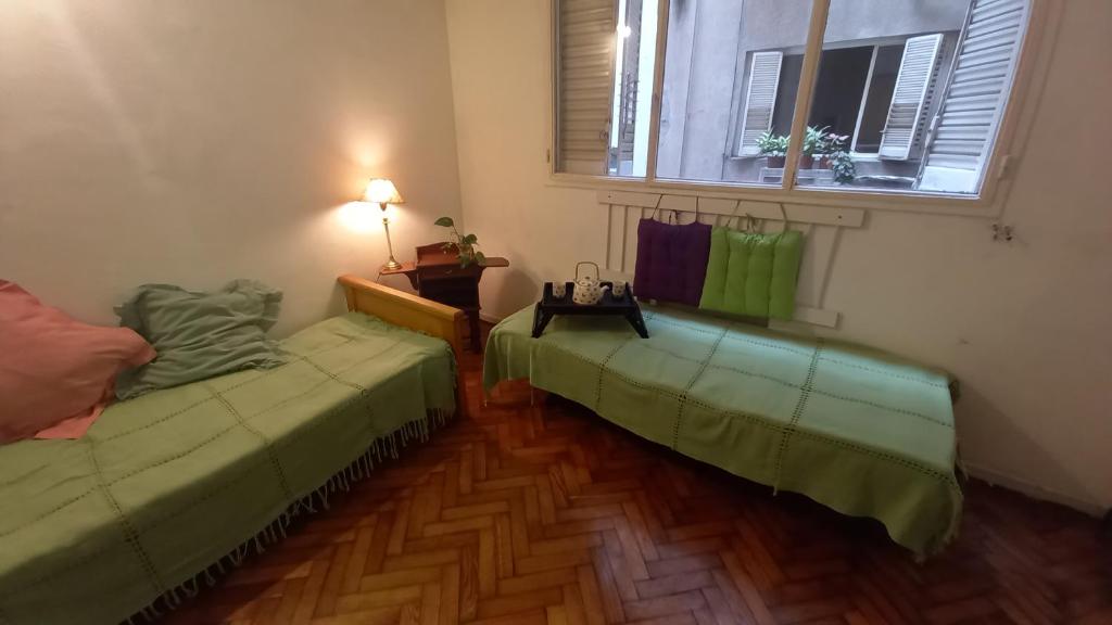 Habitación con 2 camas verdes y ventana. en Depto en recolecta en Buenos Aires