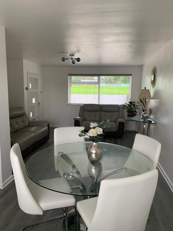 een woonkamer met een glazen tafel en witte stoelen bij Adsa Guesthouse in Seacroft