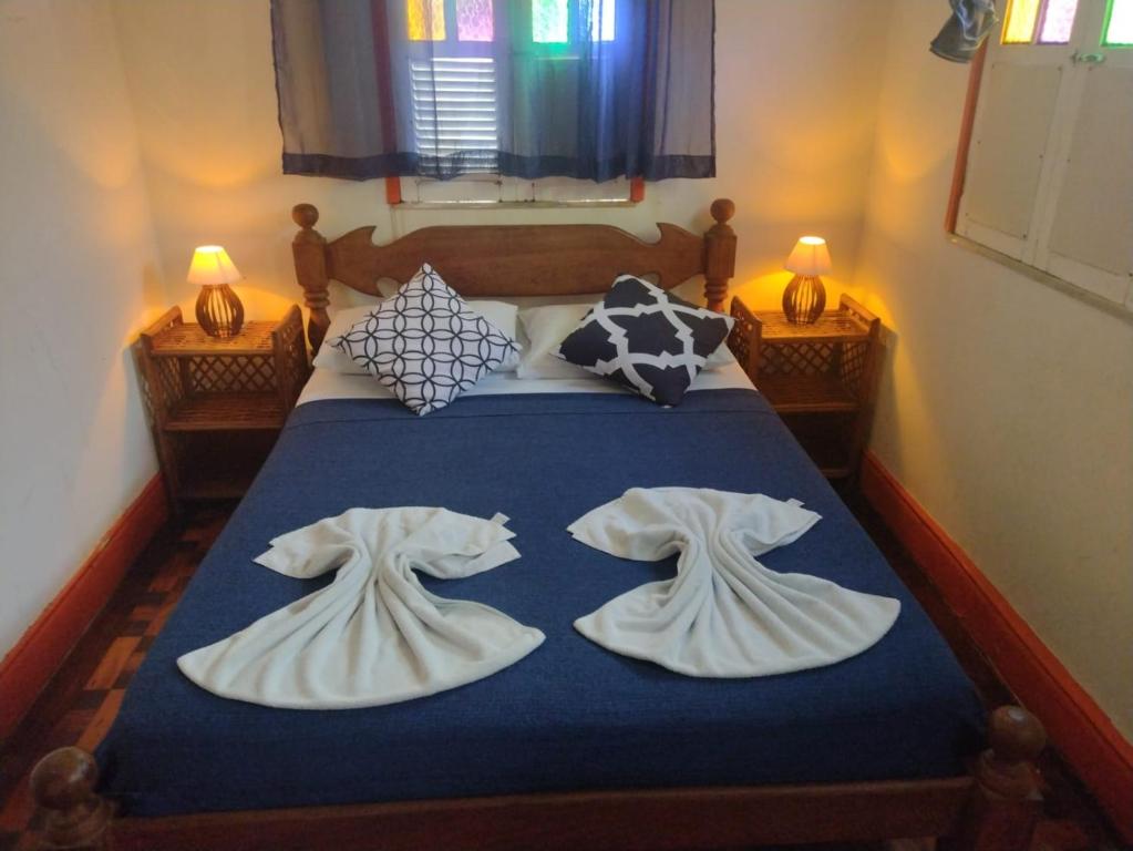 Una cama con sábanas blancas y almohadas. en Pousada Bamboo da Barra, en Salvador