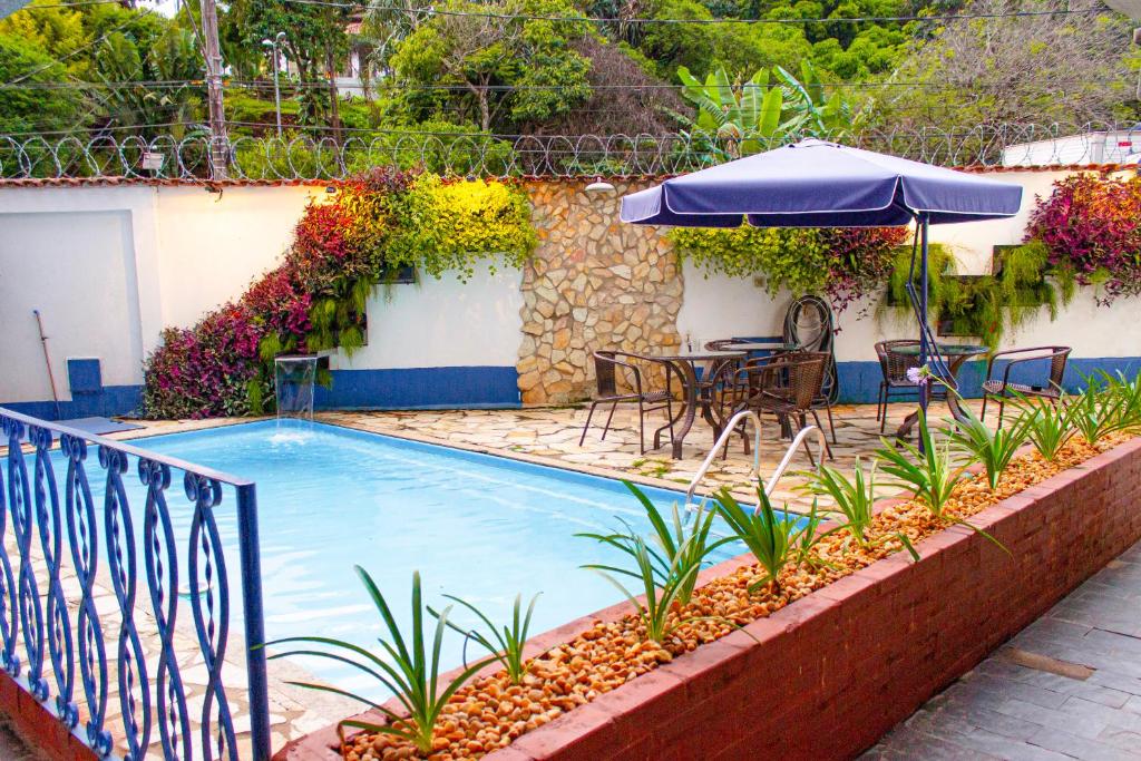 uma piscina com uma mesa e um guarda-sol em Pousada Villa Real em Sabará