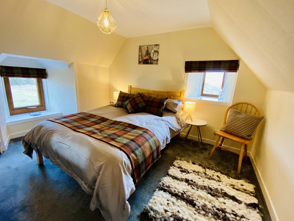 a bedroom with a bed and a chair and windows at Croft House, Armadale Bay in Armadale