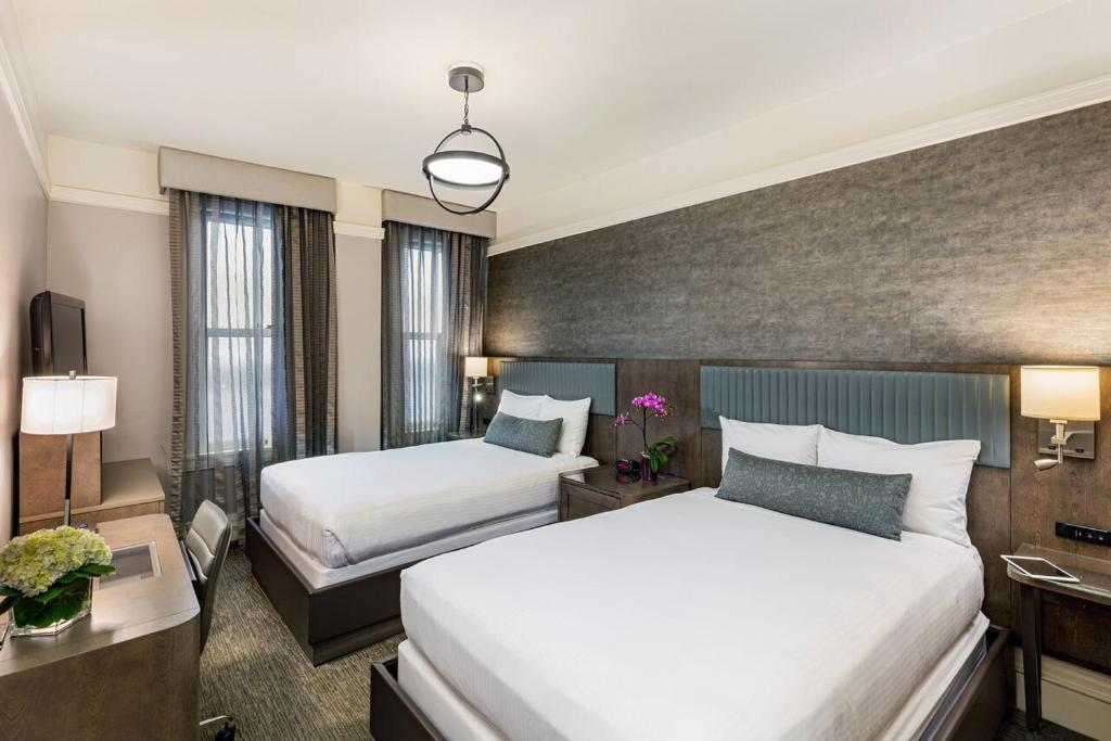 a hotel room with two beds and a desk at Handlery Union Square Hotel in San Francisco