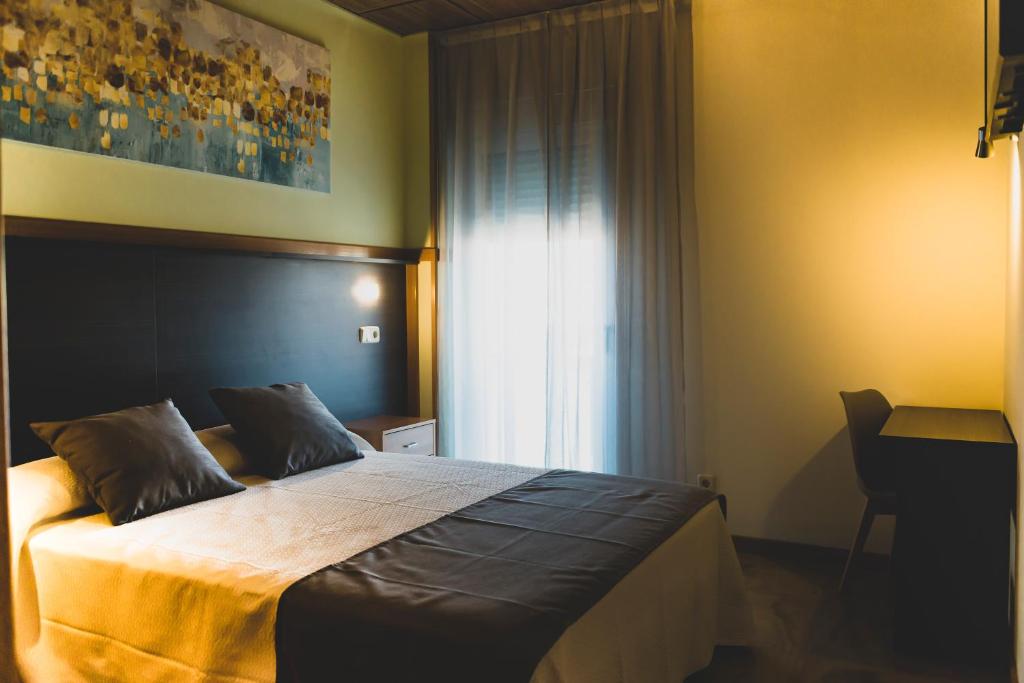 um quarto com uma cama, uma janela e uma secretária em HOSTAL NOGUERAS 3 em Toledo