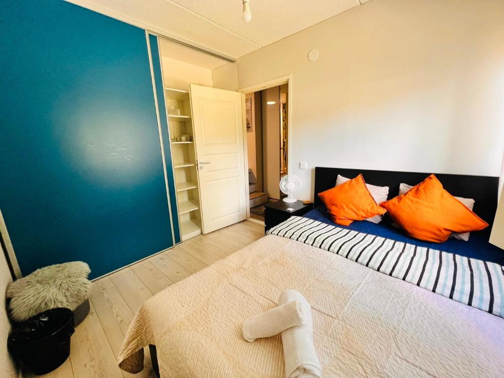 1 dormitorio con 1 cama grande con almohadas de color naranja en Cozy private room with free parking and sauna en Vantaa