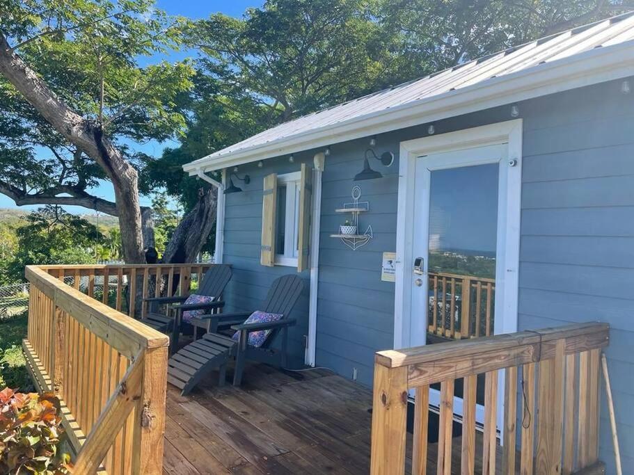 una casa blu con portico in legno e porta di Vista Mar y Tierra - Tiny House on an acre with ocean view 