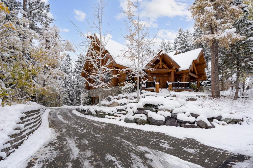 una escena de invierno de una cabaña de madera con una entrada cubierta de nieve en The Grand Alpine Lodge, en Whitefish