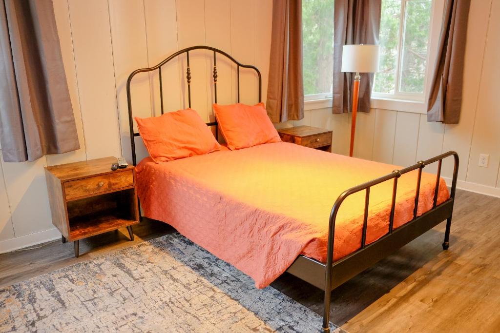 a bedroom with a bed with an orange comforter at Sherwood Arms Motel in Running Springs