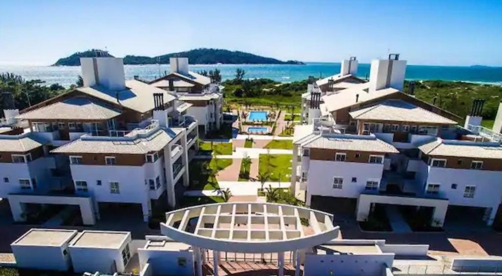 Vista ariale di un resort con l'oceano sullo sfondo di Apartamento pé na areia em frente a Ilha do Campeche a Florianópolis