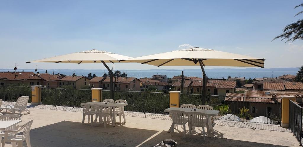 patio ze stołami, krzesłami i parasolami w obiekcie Villa Sergio w mieście Bardolino